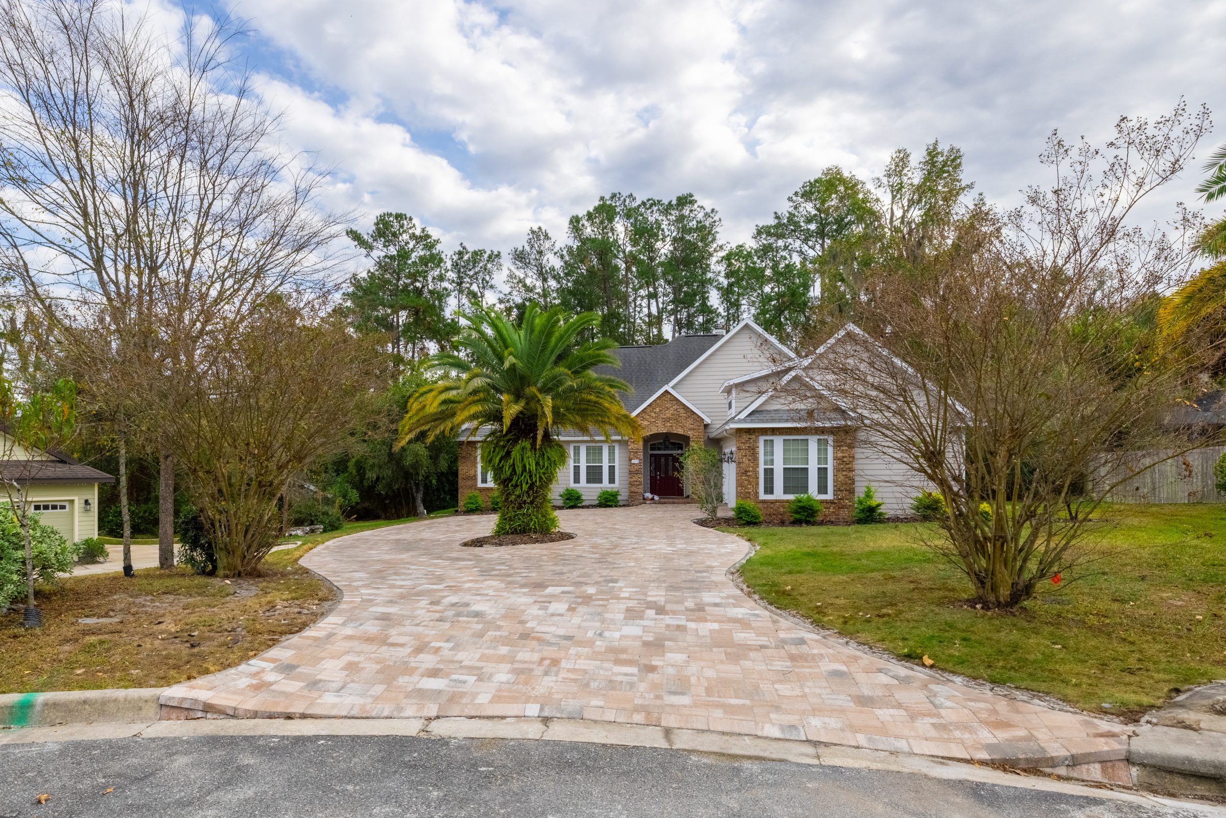 Brick home with palm-centered paver driveway