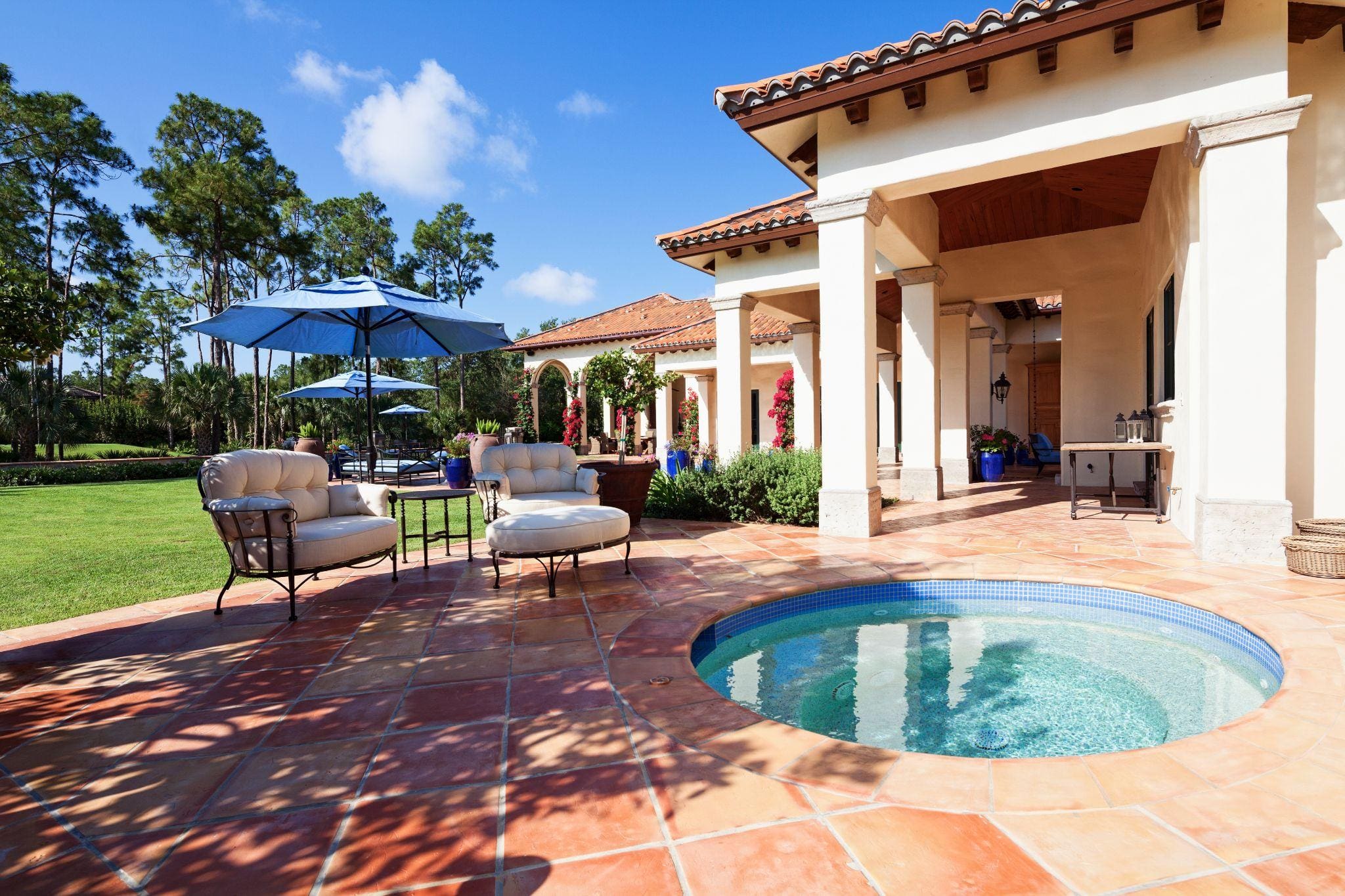A tan stone patio with a hot tub set into it.