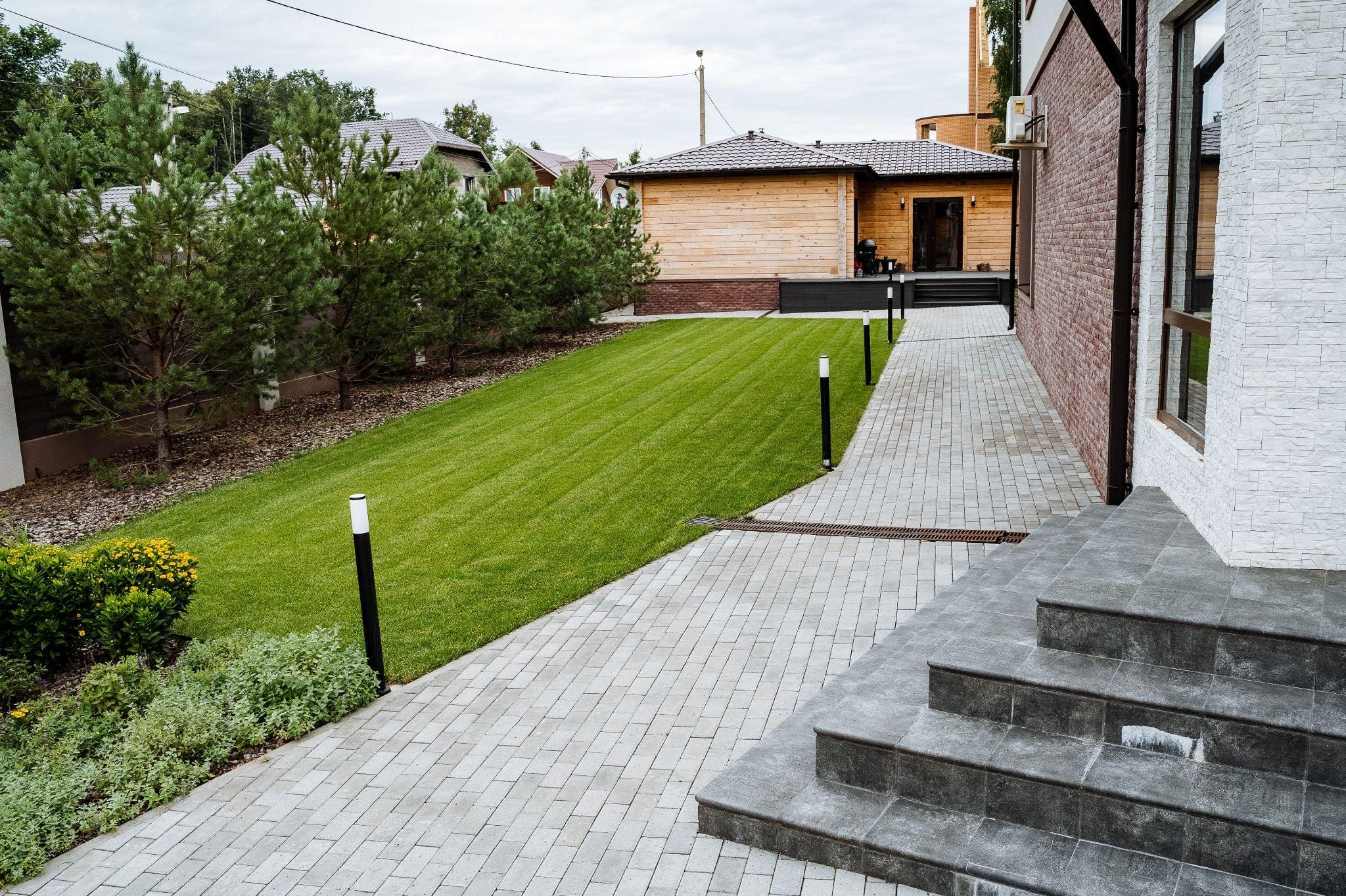 A row of modern houses with various designs, featuring clean lines and a well-maintained sidewalk in a sunny neighborhood.
