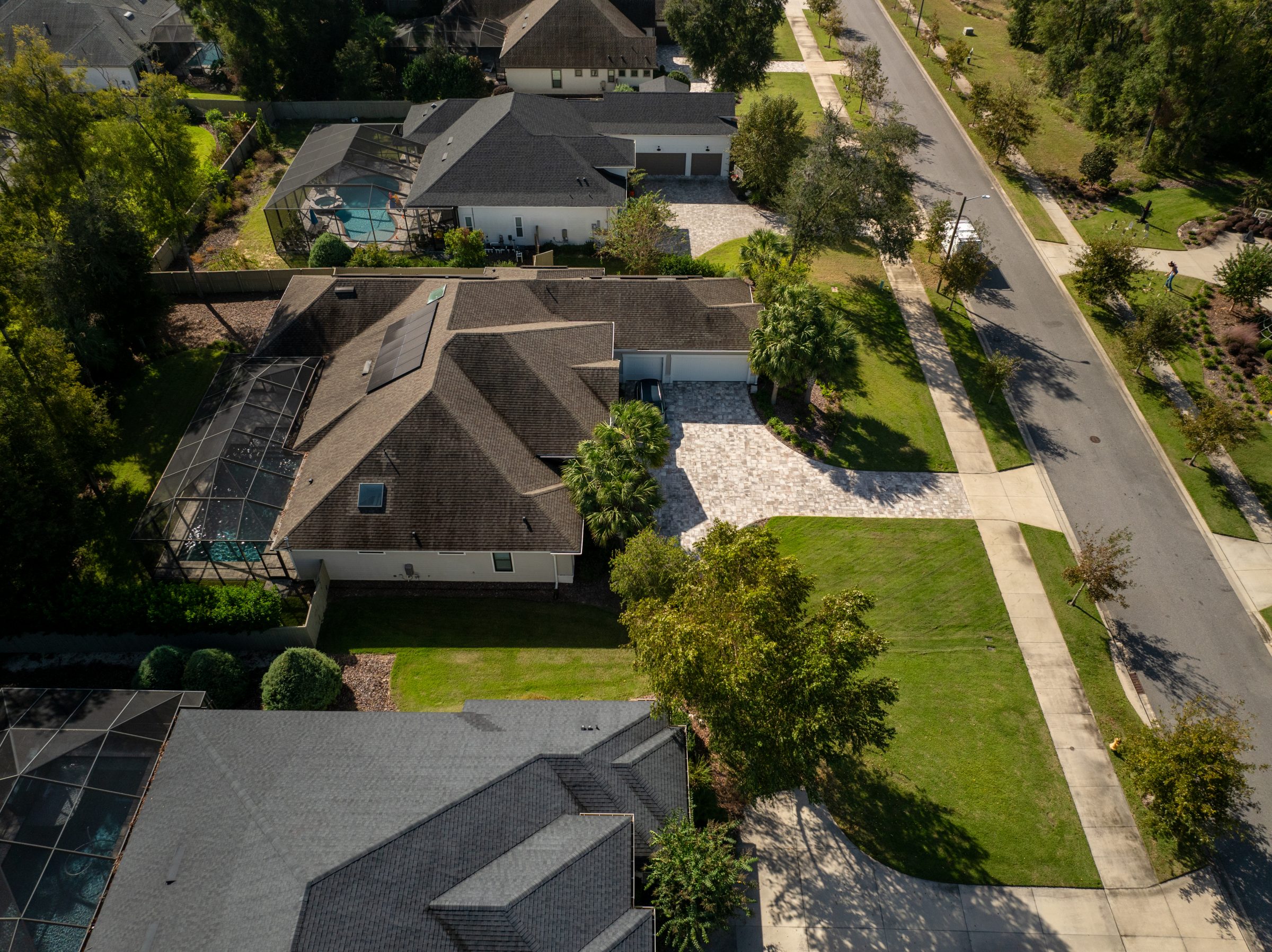 Aerial view of suburban homes with screened pools