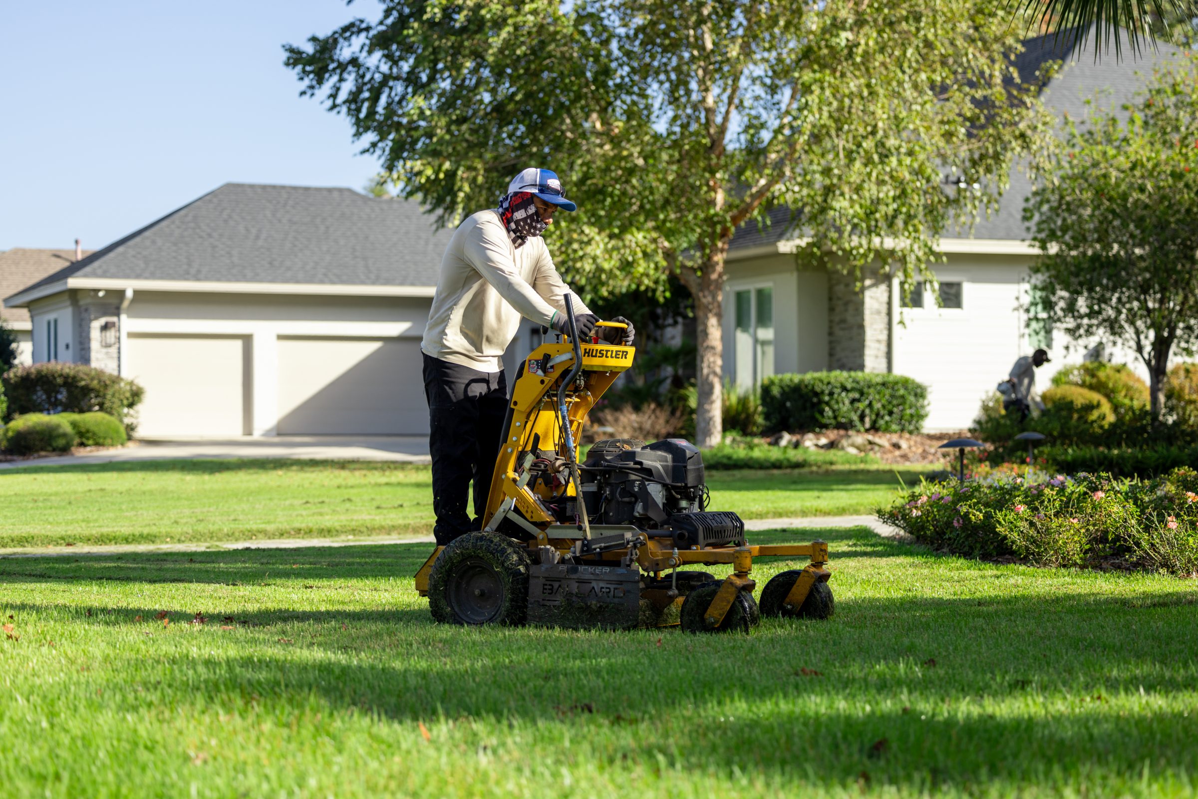 Landscaper mowing a suburban home's green front lawn