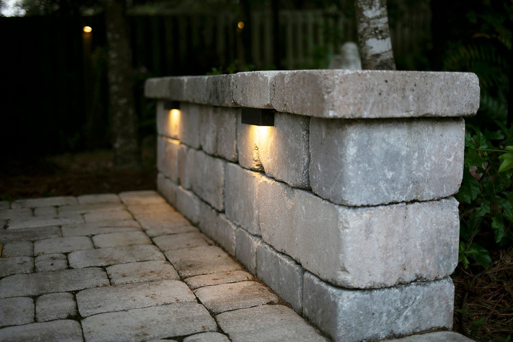 Stone retaining wall with glowing recessed pathway lights