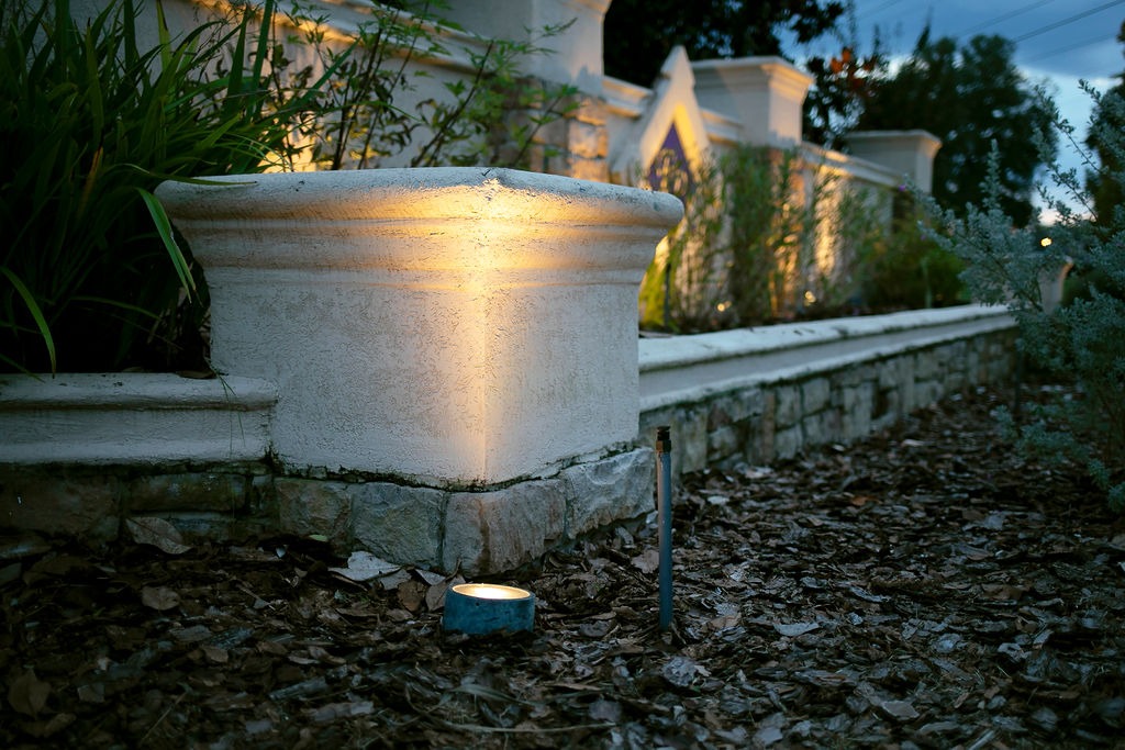 Landscape uplight illuminating a stone garden planter at dusk