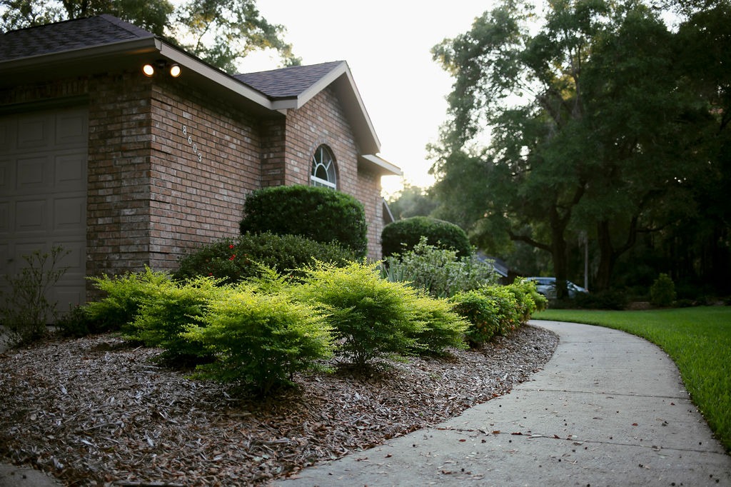 Curved walkway beside brick house and landscaped shrubs
