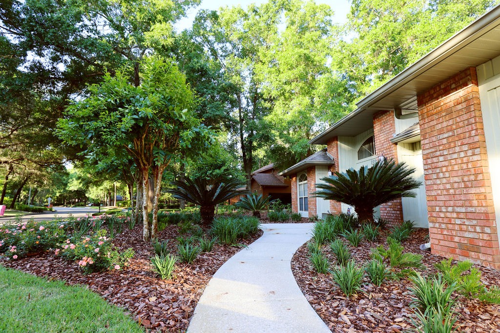 Curved walkway beside brick home and landscaped garden