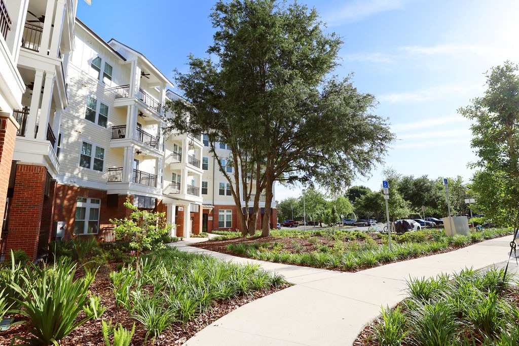 Landscaped walkway beside modern apartment building and trees
