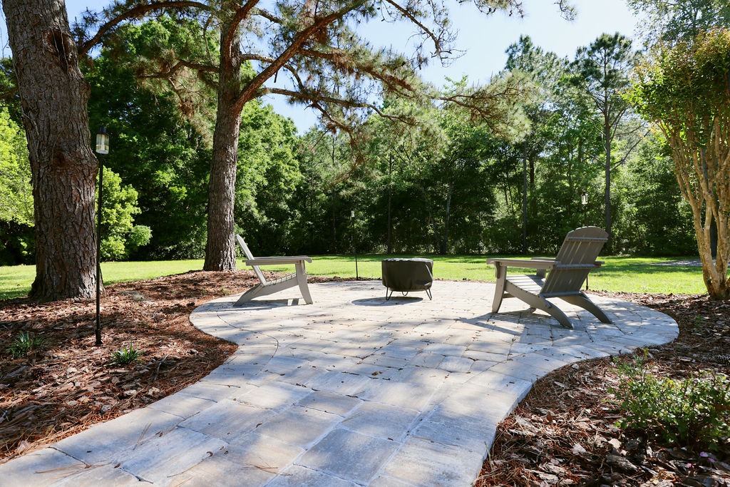 Stone patio with Adirondack chairs beneath tall pine trees
