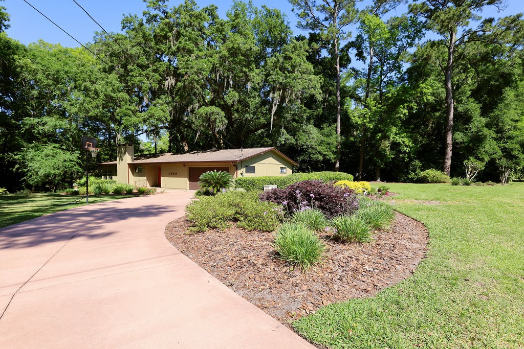 Landscaped ranch home with curved driveway and basketball hoop