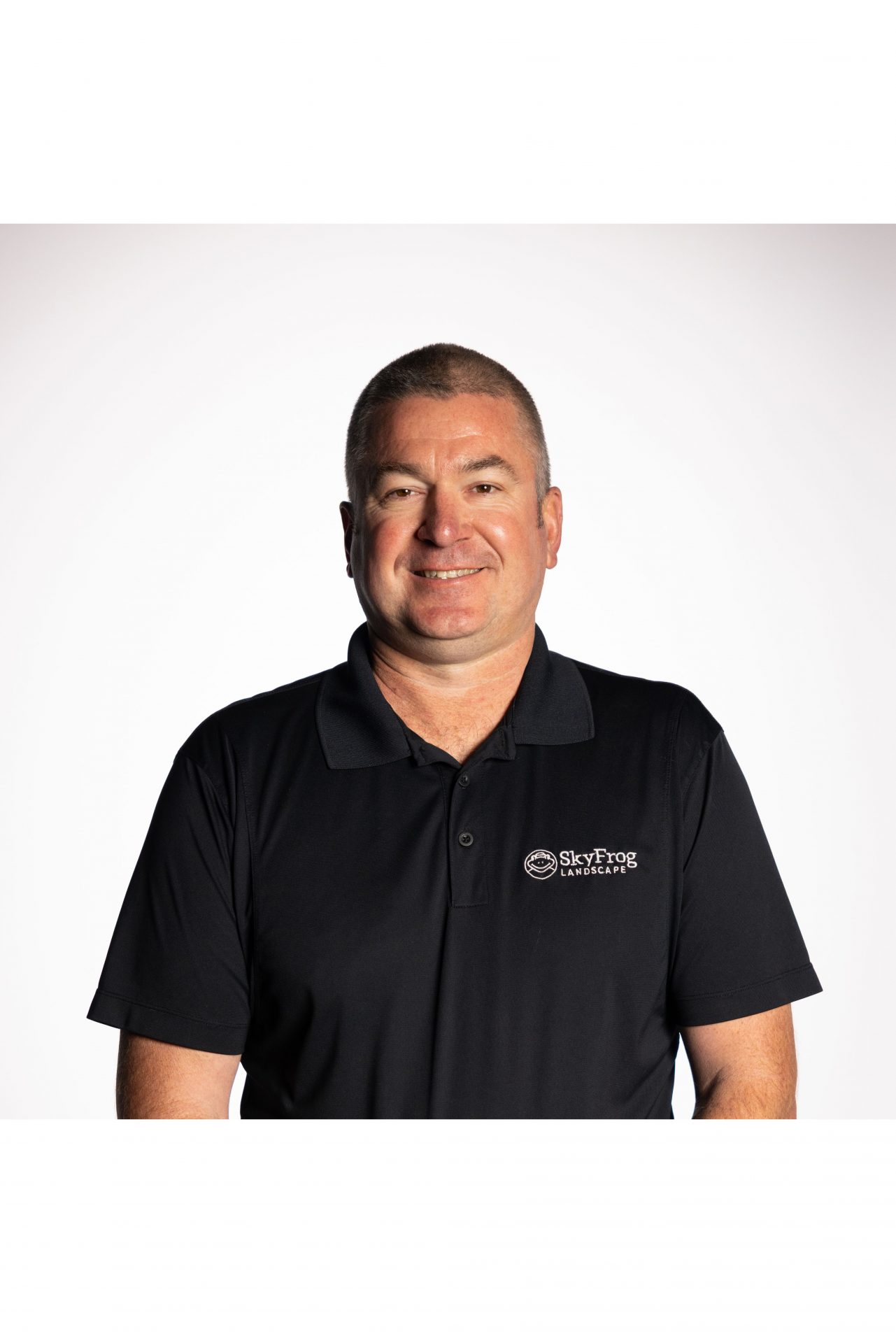 Smiling SkyFrog Landscape employee in black polo