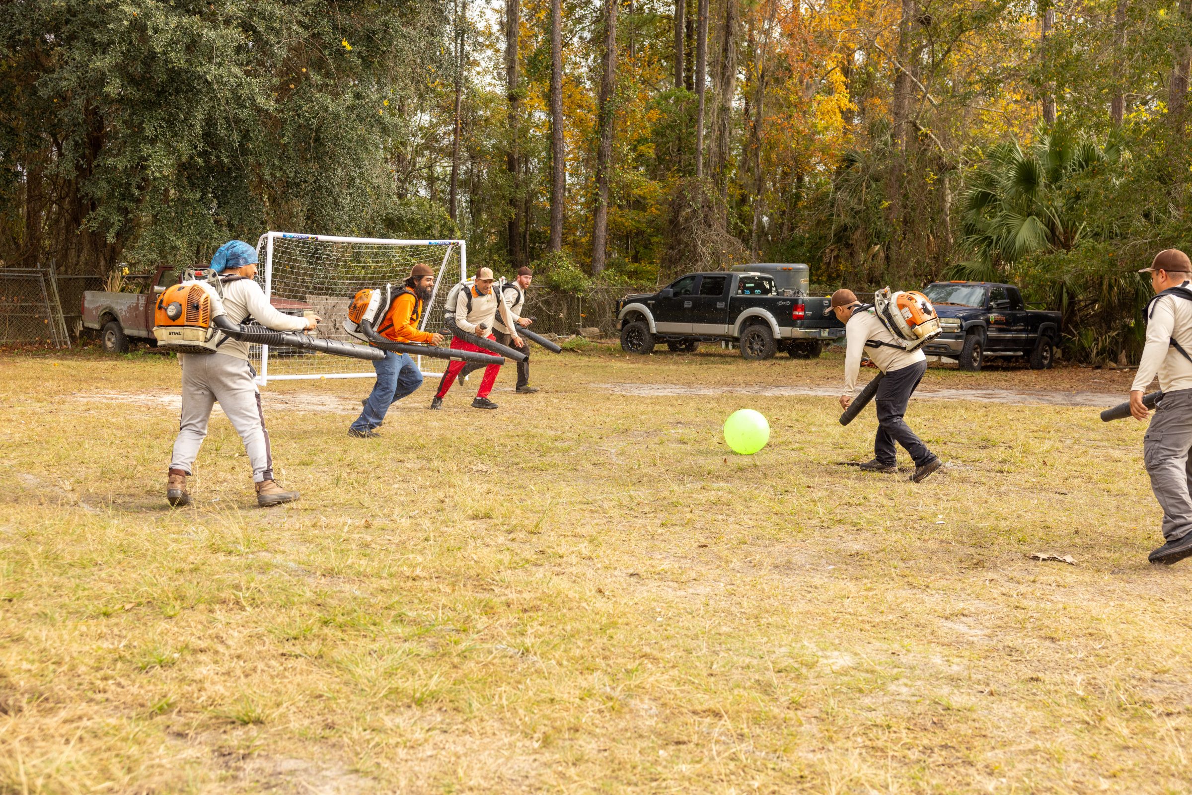 Workers use leaf blowers beside a soccer goal