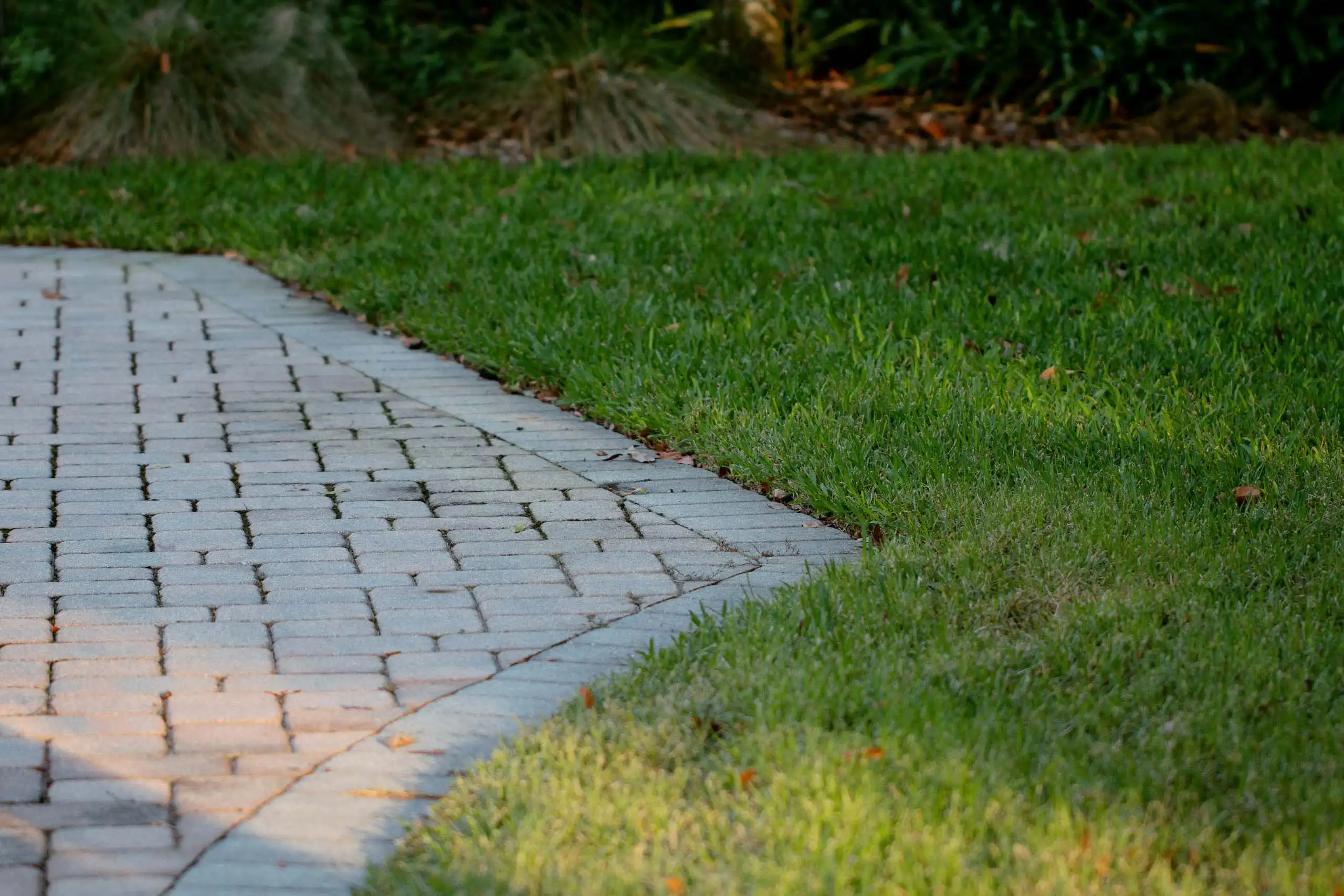 Curving stone walkway beside a lush green lawn