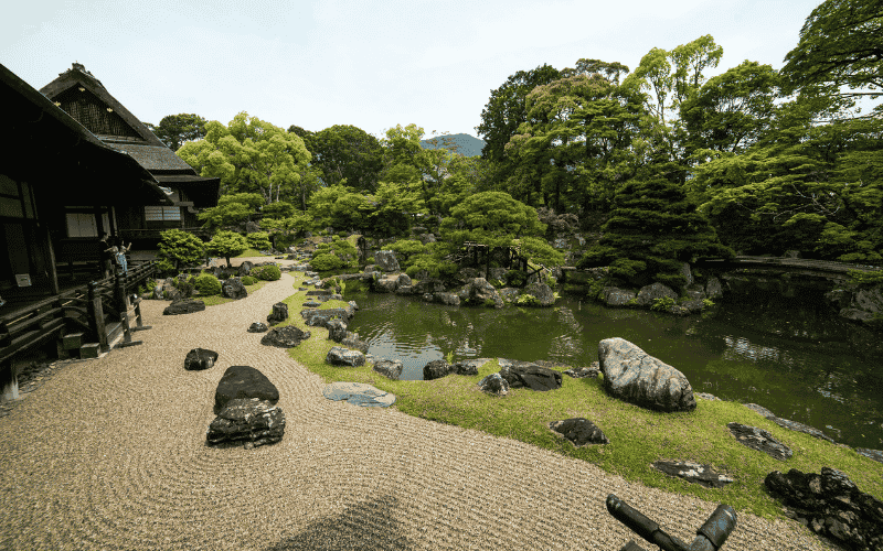 Japanese rock garden with pond, trees, and traditional building