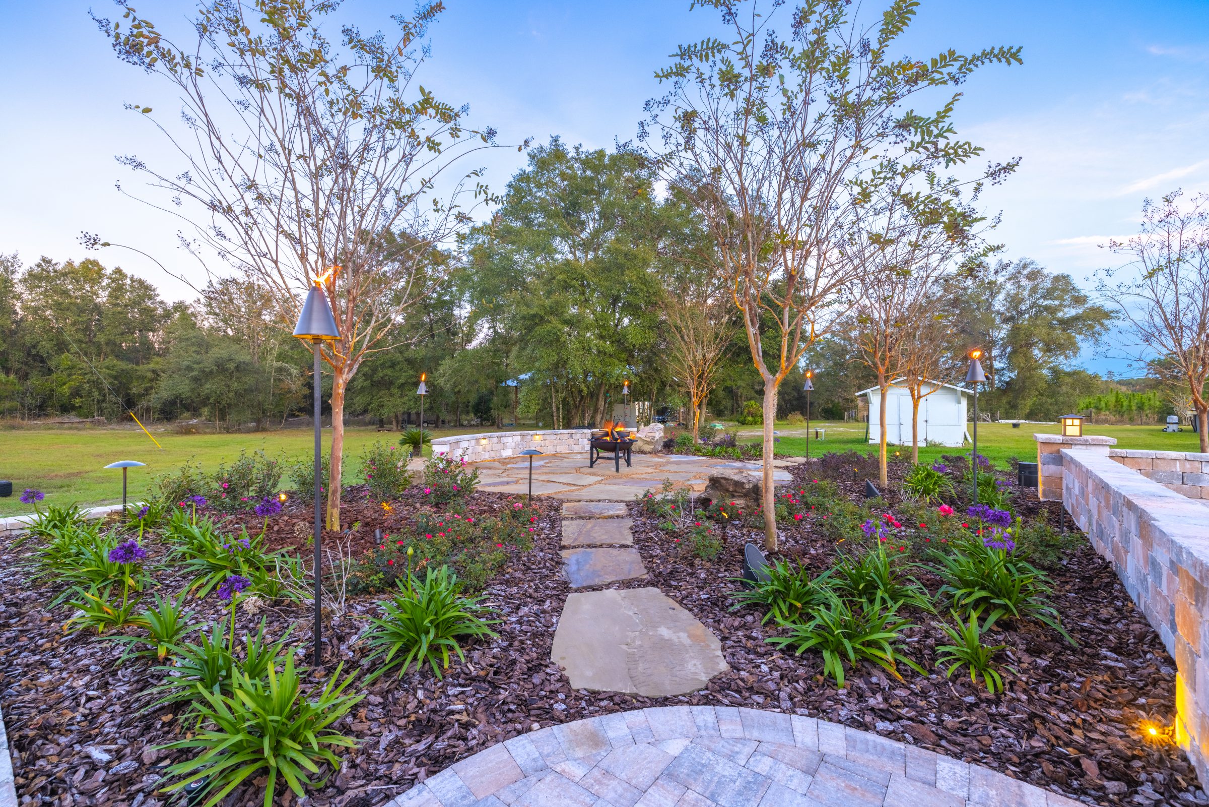 Landscaped garden path leading to a glowing fire pit