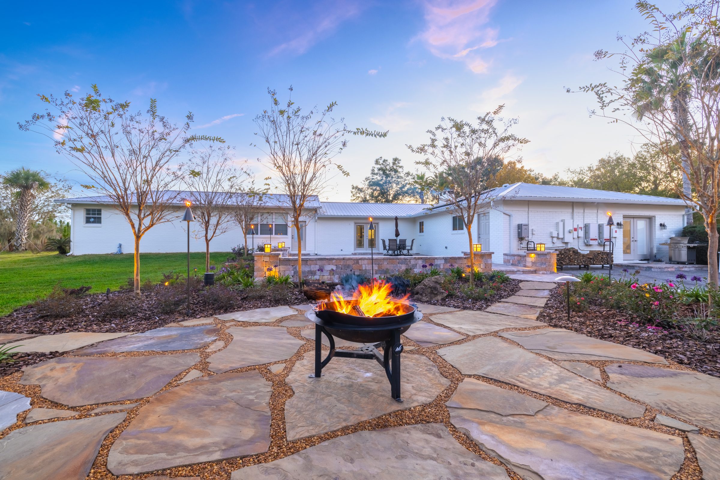 Fire pit patio outside white home at dusk