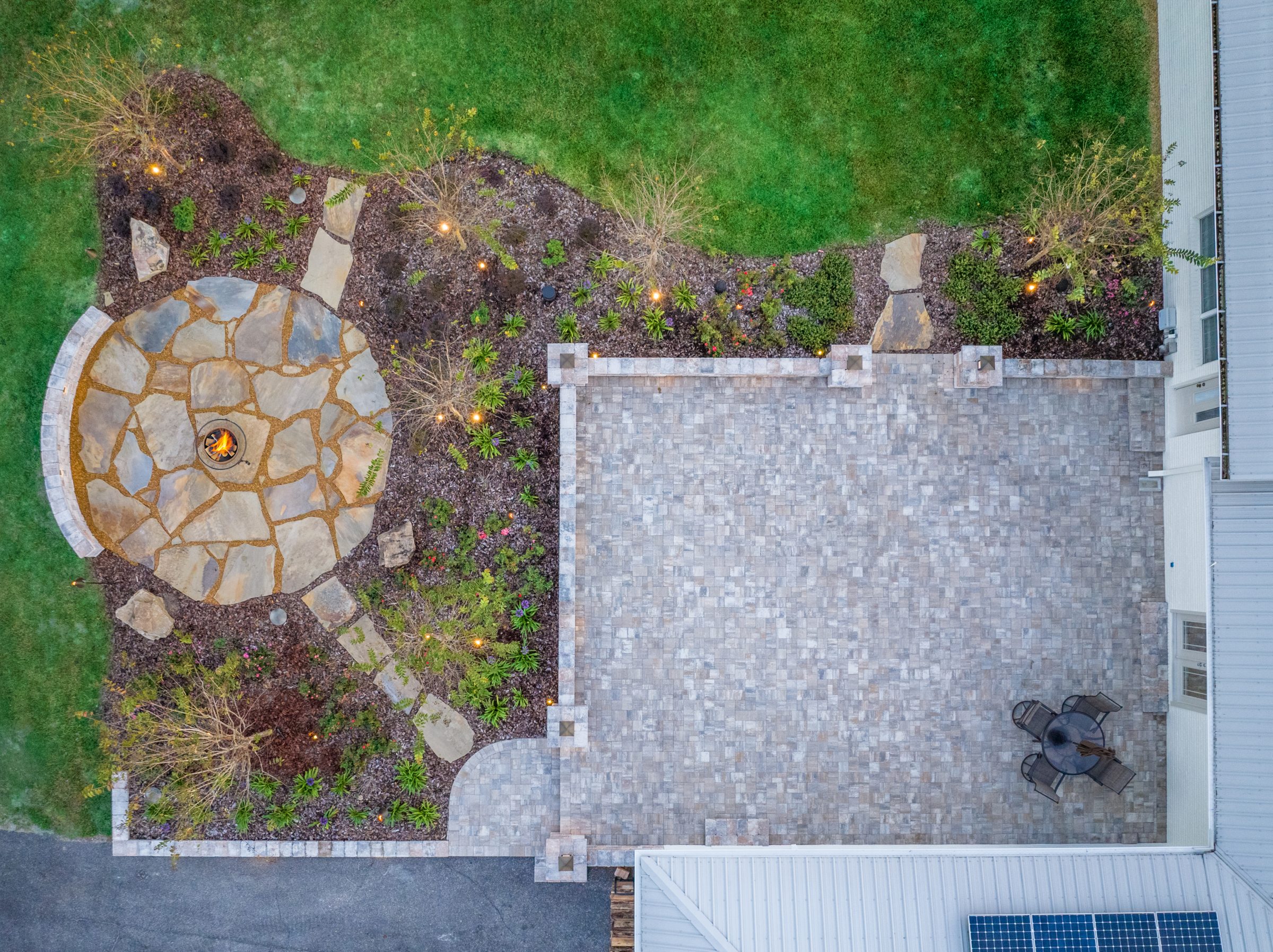 Aerial view of patio, garden, and lit fire pit