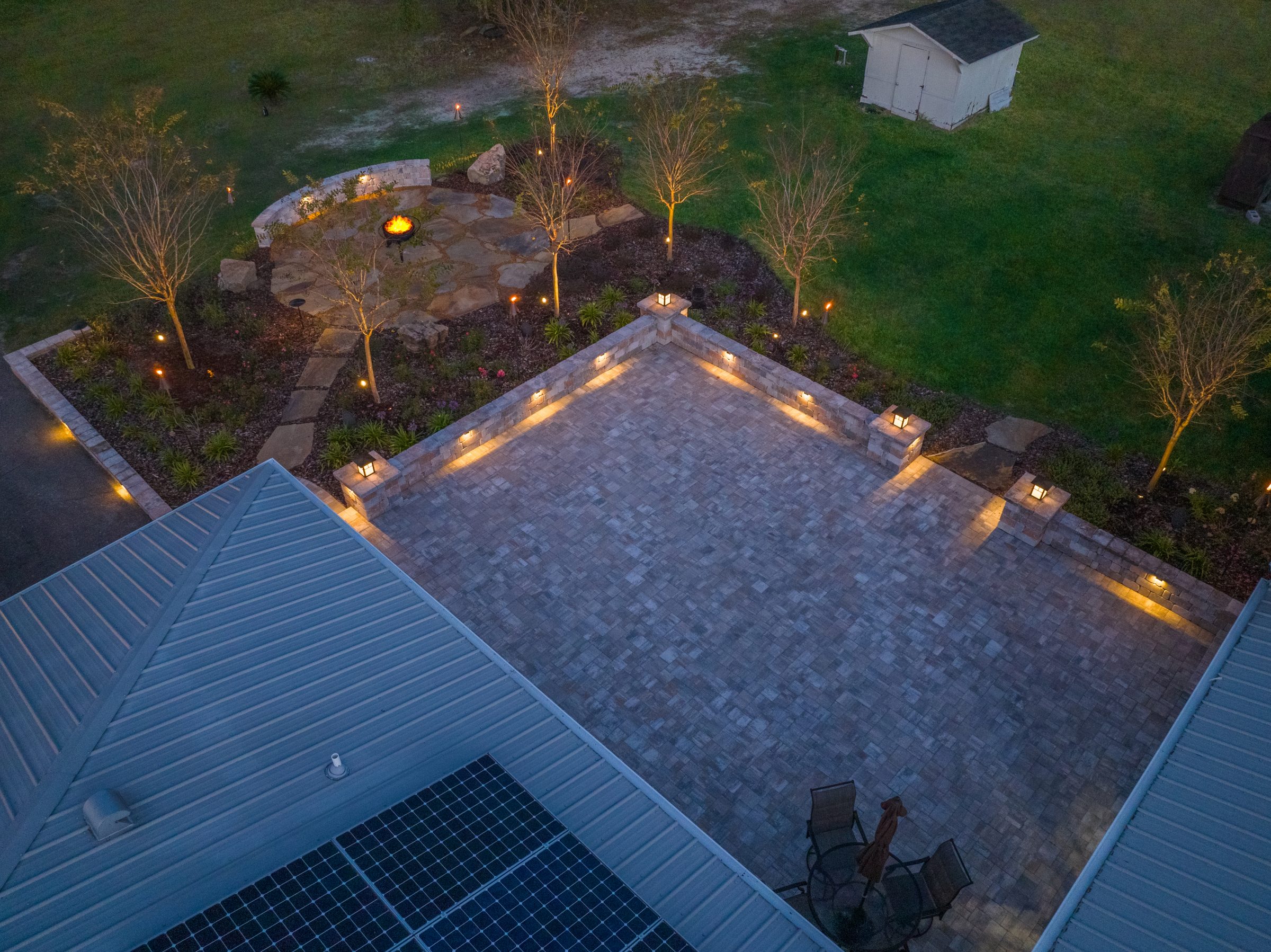 Twilight aerial view of illuminated patio and fire pit
