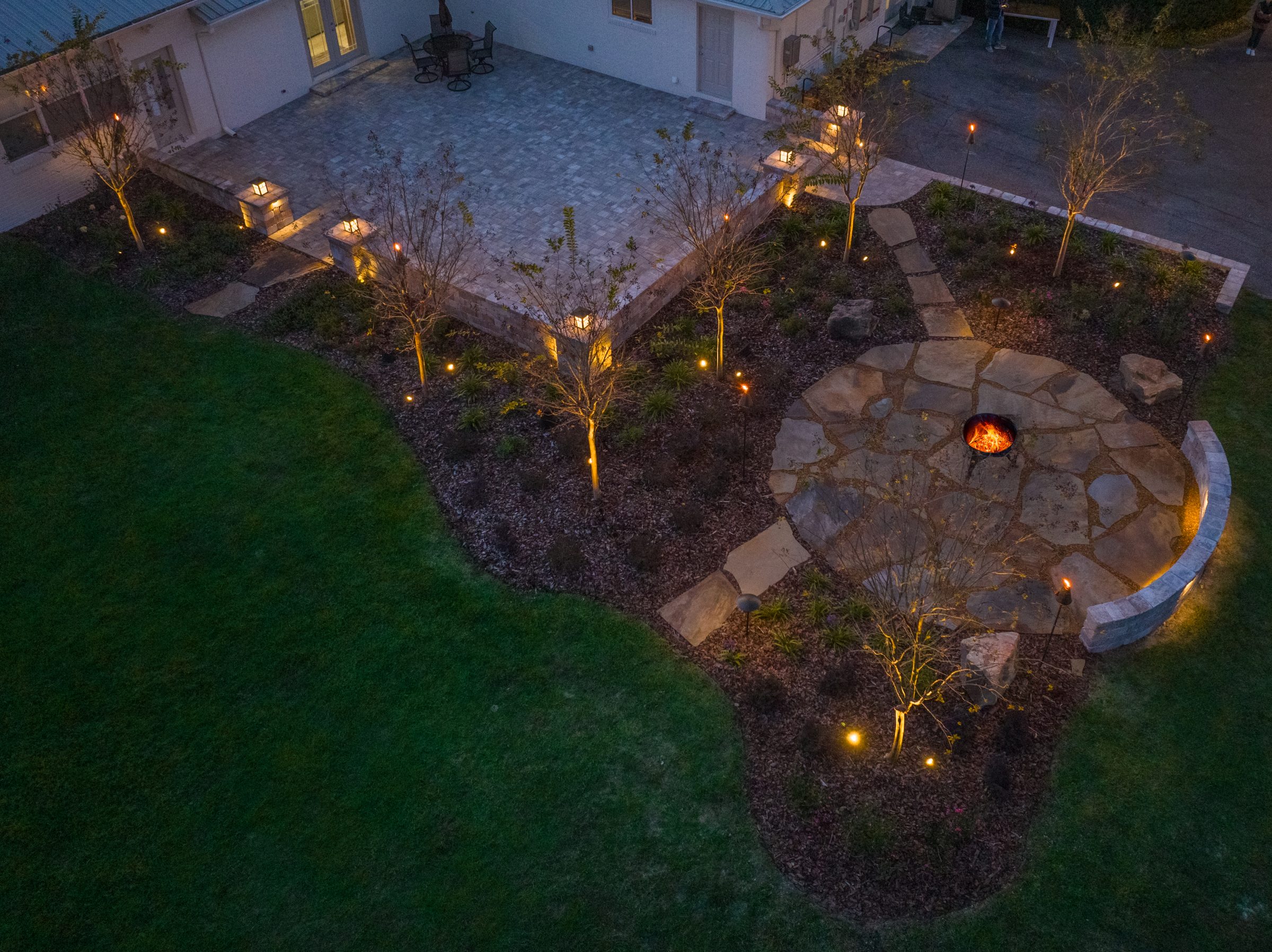 Illuminated backyard patio and fire pit at dusk