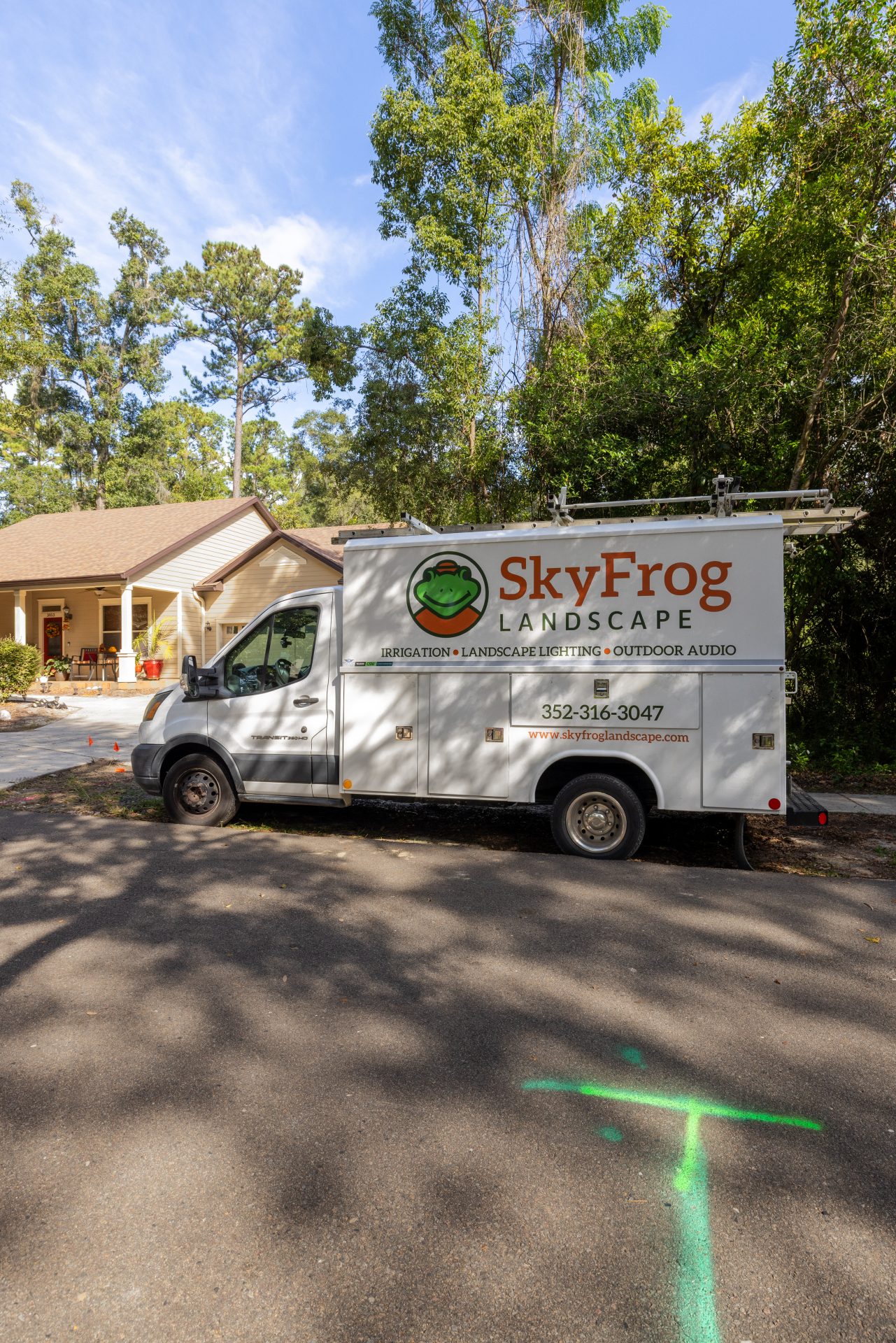 SkyFrog Landscape service truck parked outside a wooded home