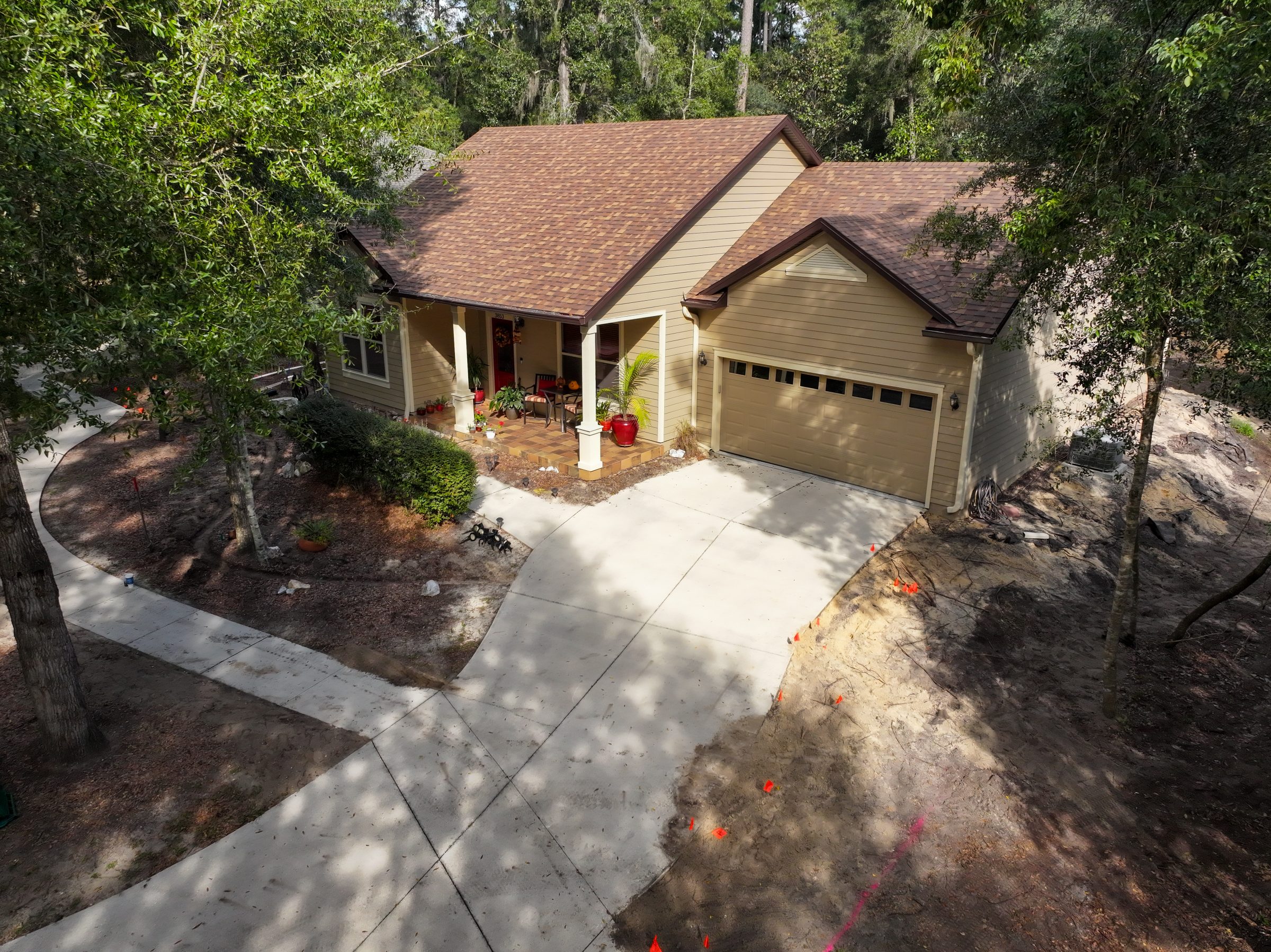 Wooded suburban home with driveway, garage, and front porch