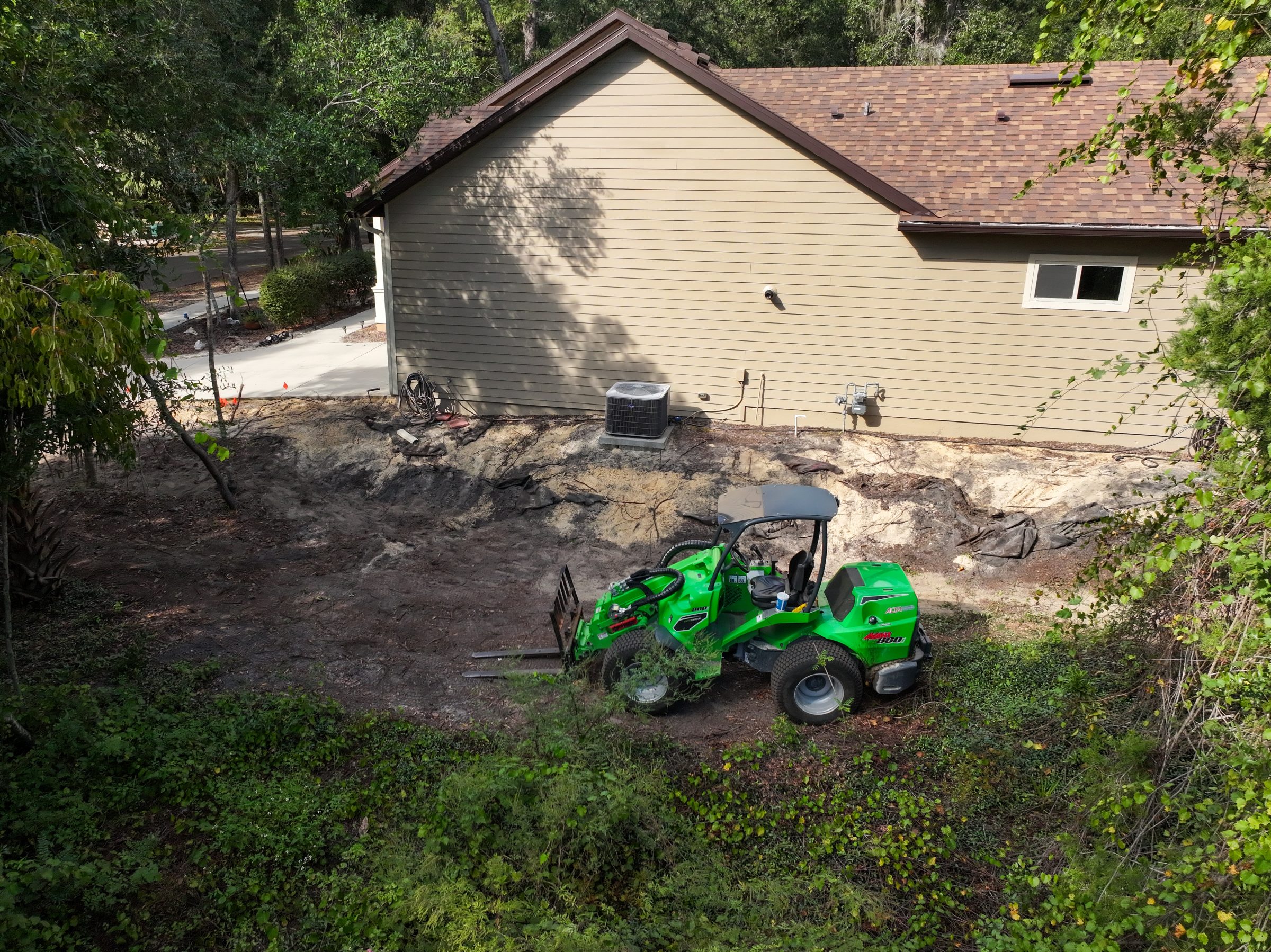 Green mower beside house during backyard landscaping project
