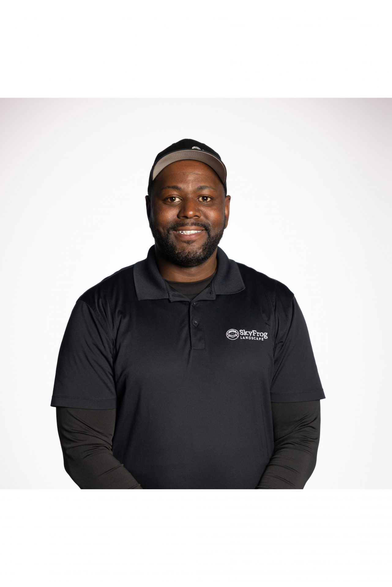 Smiling SkyFrog Landscapes employee in black uniform and cap