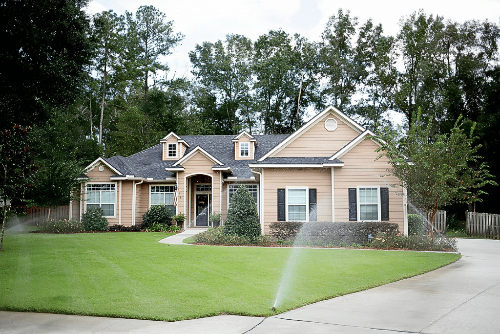 Beige suburban home with manicured lawn and sprinklers