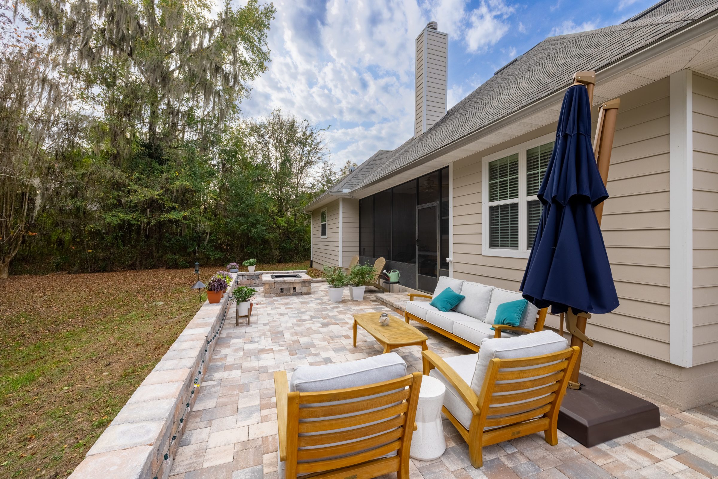 Cozy patio seating beside screened porch and wooded backyard