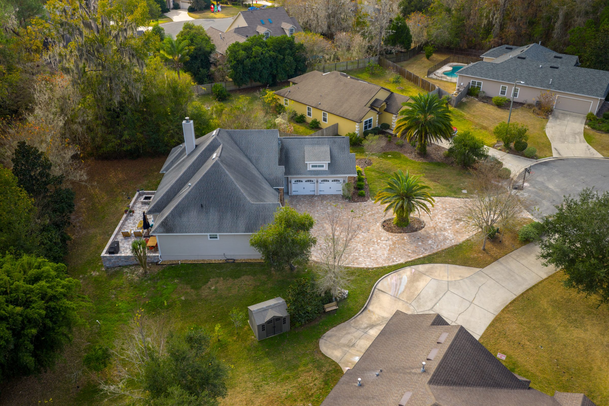 Aerial view of suburban home with palm-lined circular driveway