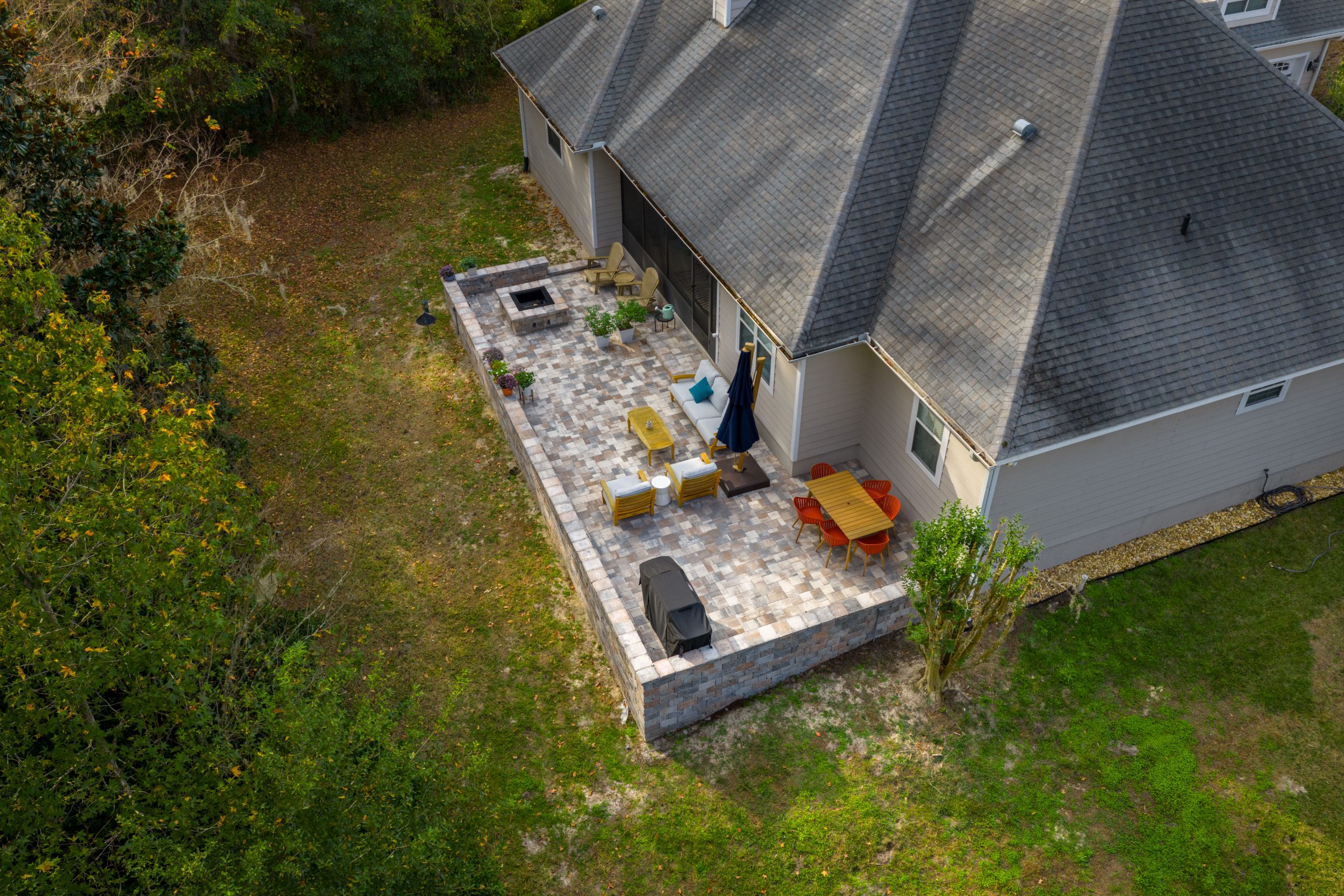 Aerial view of furnished backyard patio beside suburban home