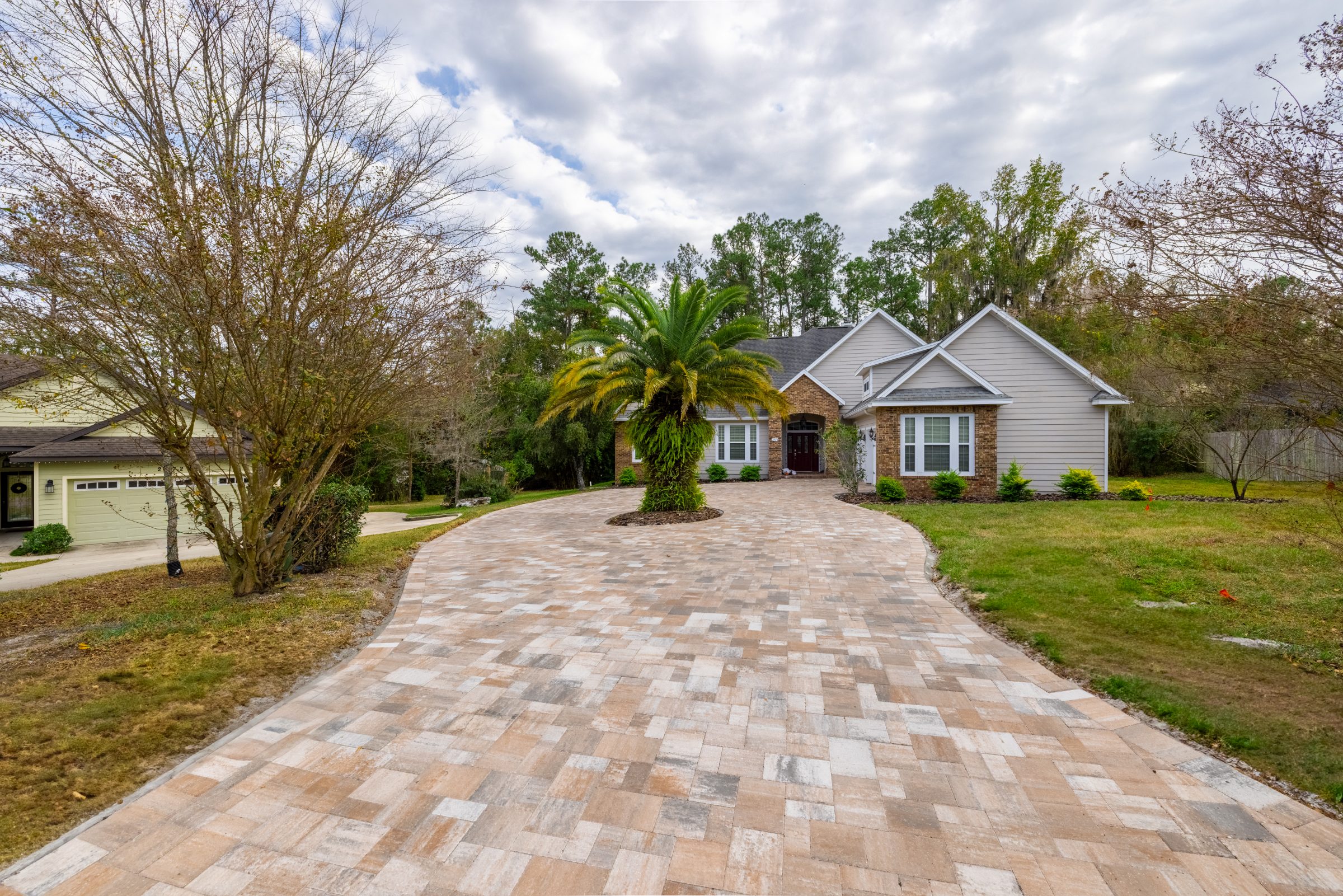 Brick home with palm tree and paved circular driveway