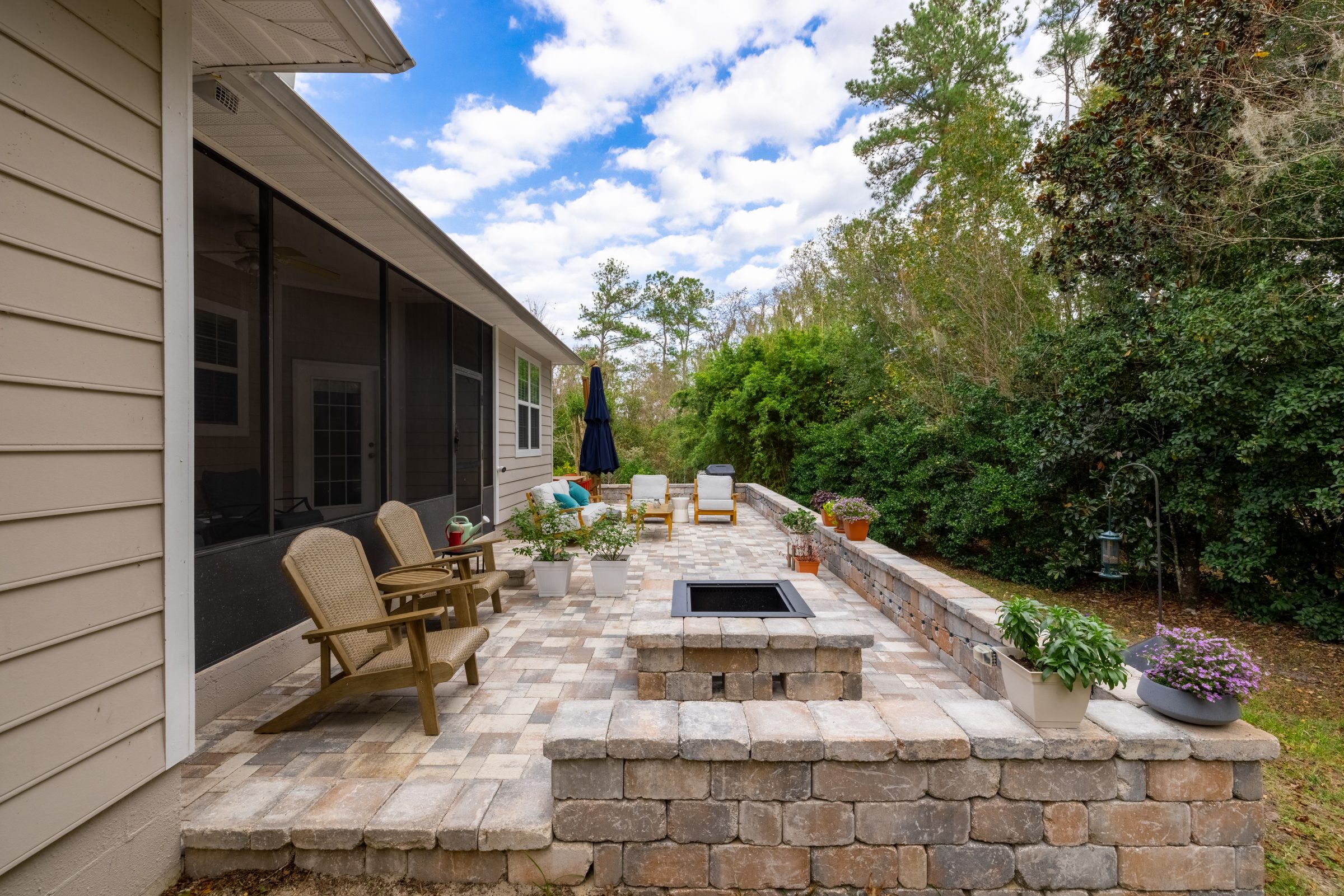 Landscaped patio with fire pit, chairs, and screened porch