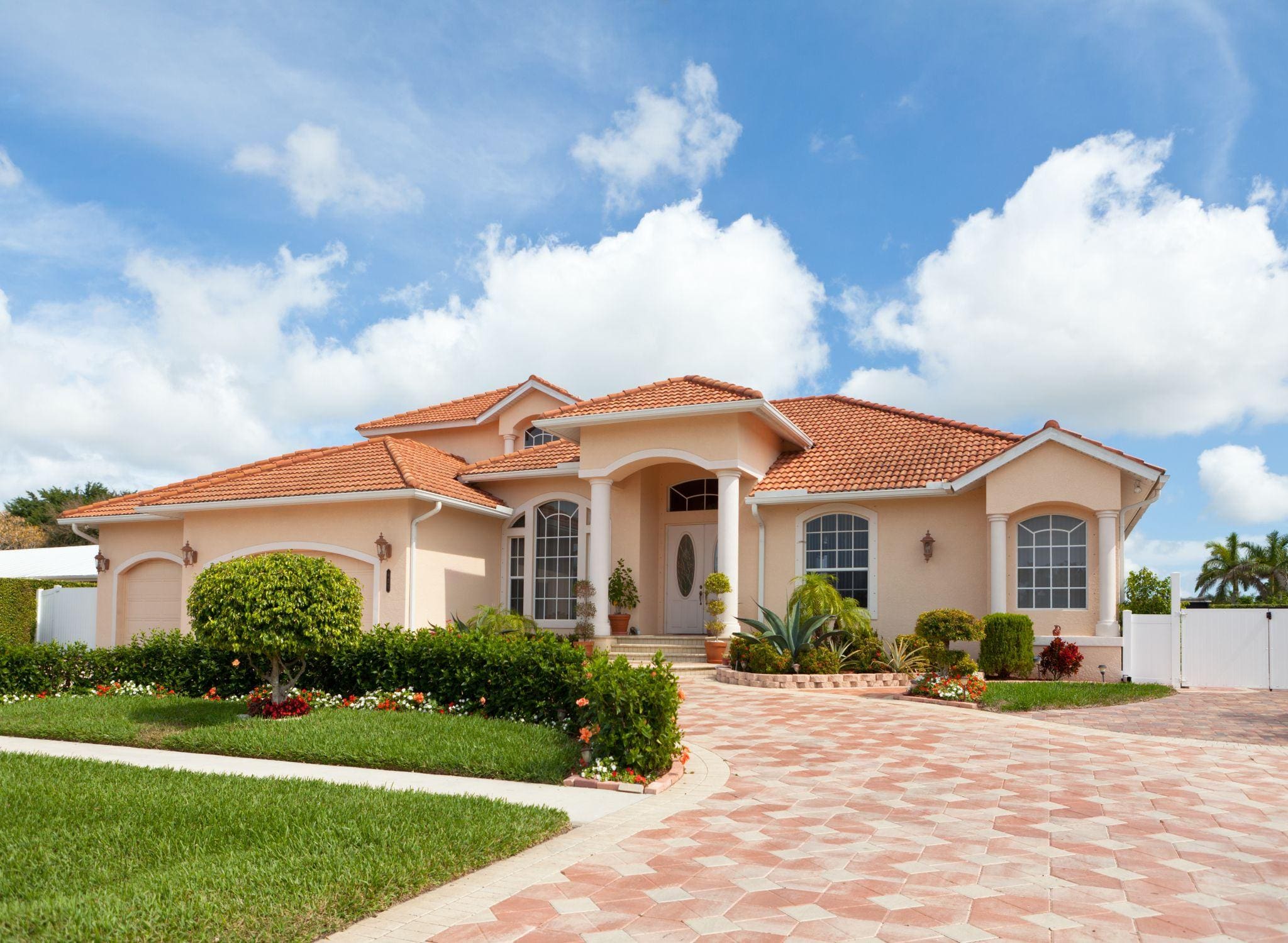 Mediterranean-style home with tiled roof and landscaped driveway