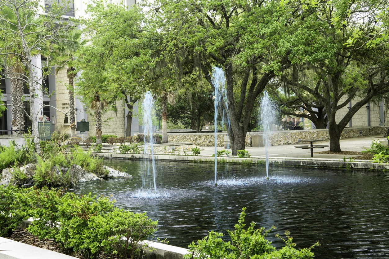 Fountains in a tree-lined pond beside a plaza