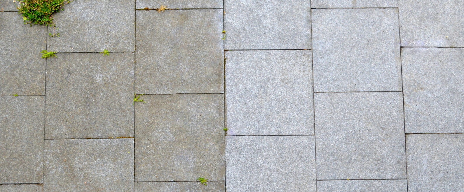 Gray stone pavement with grass growing between slabs