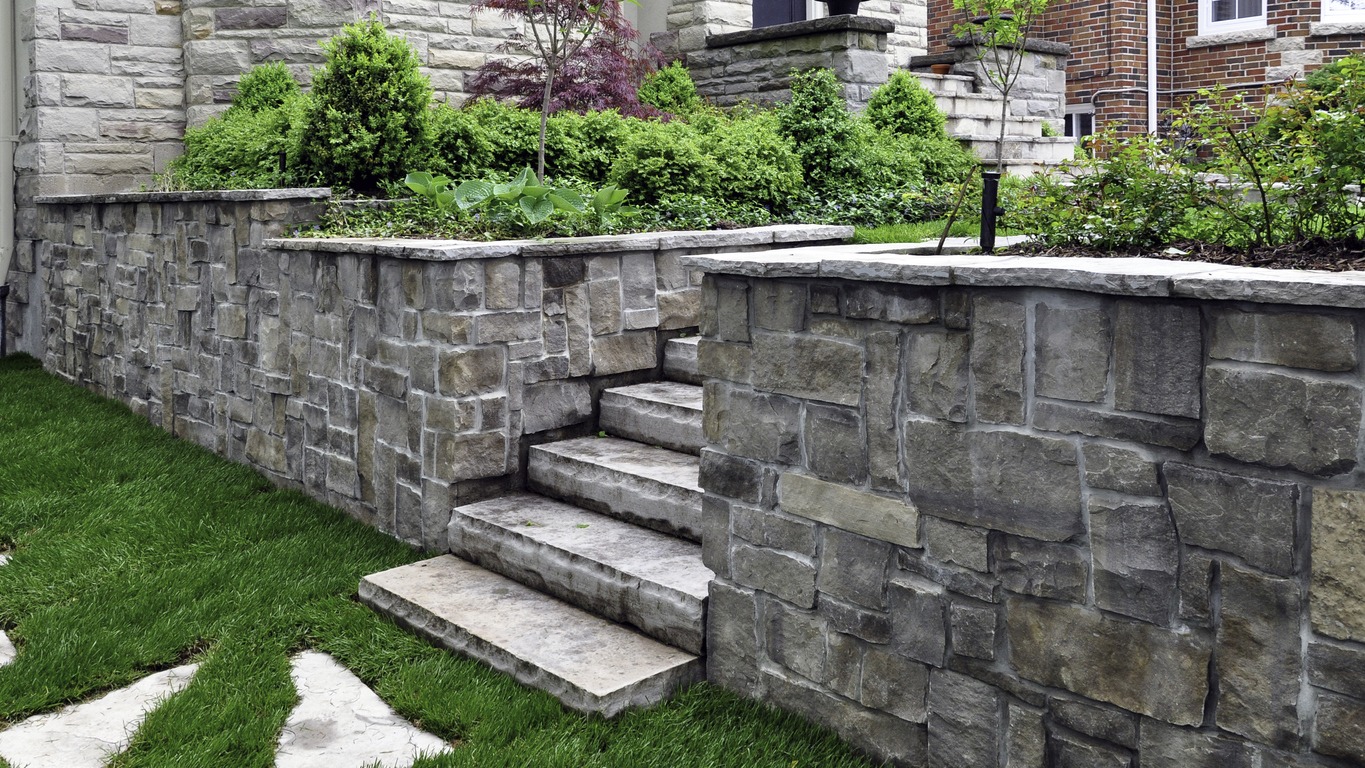 Stone retaining wall and steps beside landscaped garden