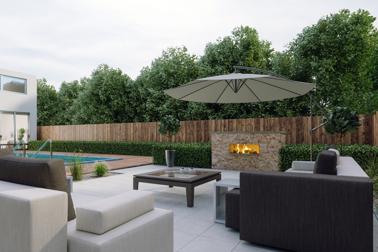 Modern patio lounge beside pool with fireplace and umbrella
