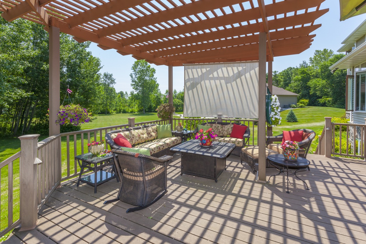 Furnished backyard deck beneath wooden pergola