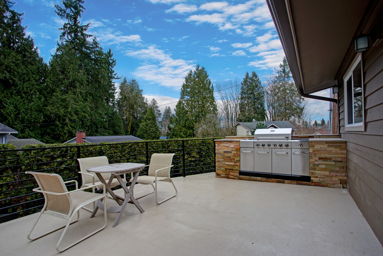Outdoor patio with seating, grill, and forest view