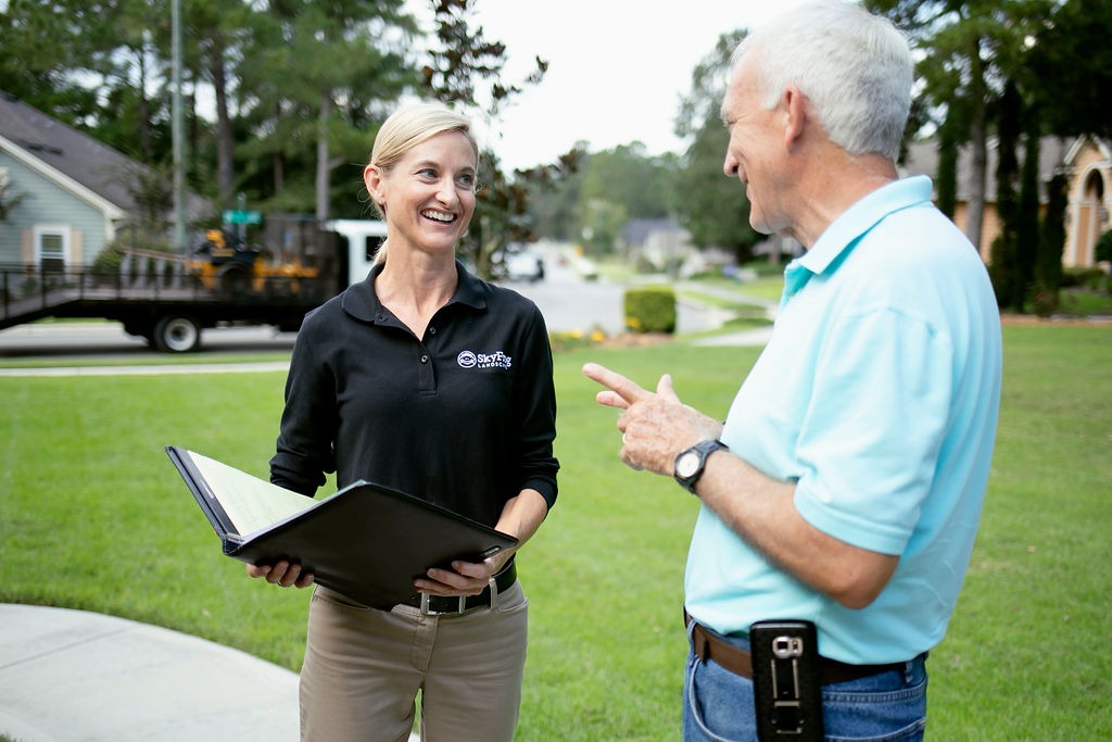 Landscaping representative discusses services with homeowner on front lawn