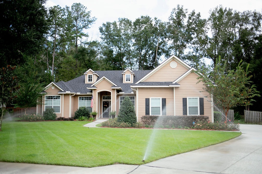 Suburban home with green lawn and sprinklers