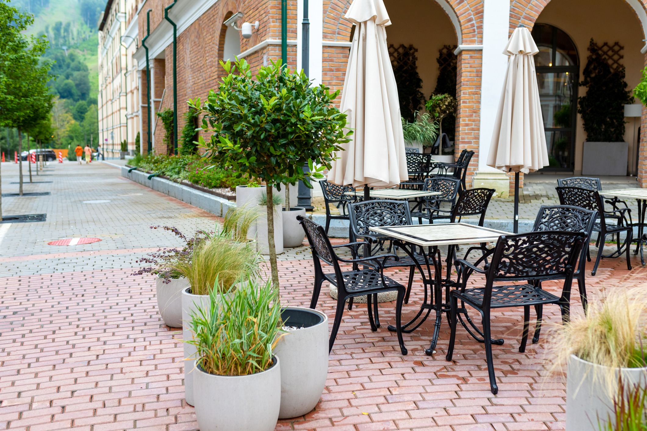 Outdoor café patio with tables, umbrellas, and brick arches