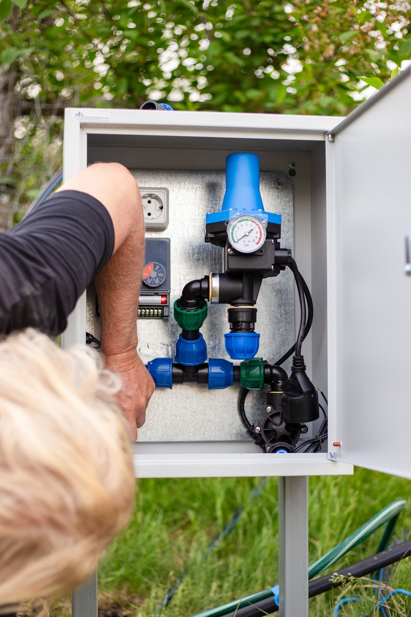 Technician adjusting outdoor irrigation control box pressure regulator